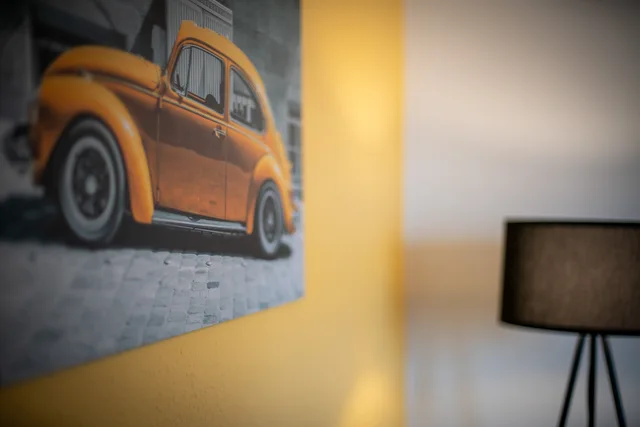 Wandbild mit gelbem VW Käfer über dem Sofa.