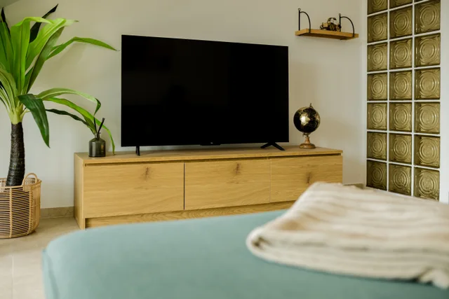 Fernseher auf dem Holzsideboard neben einer Glasbausteinwand.