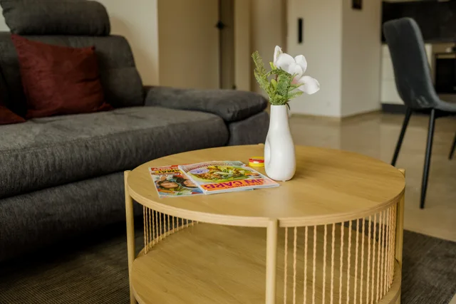 Runder Couchtisch mit Vase vor dem grauen Sofa.