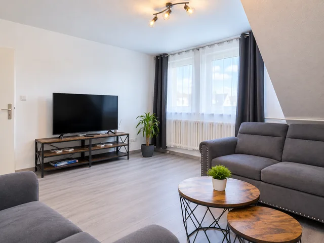 Fernseher gegenüber den Sofas im Wohnzimmer mit großem Fenster.