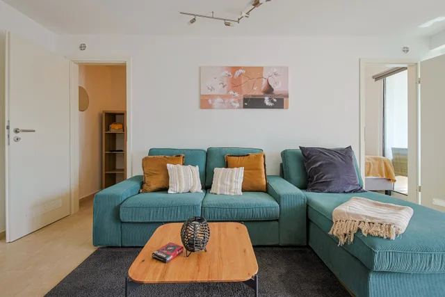Türkisfarbenes Ecksofa mit Kissen und Couchtisch.